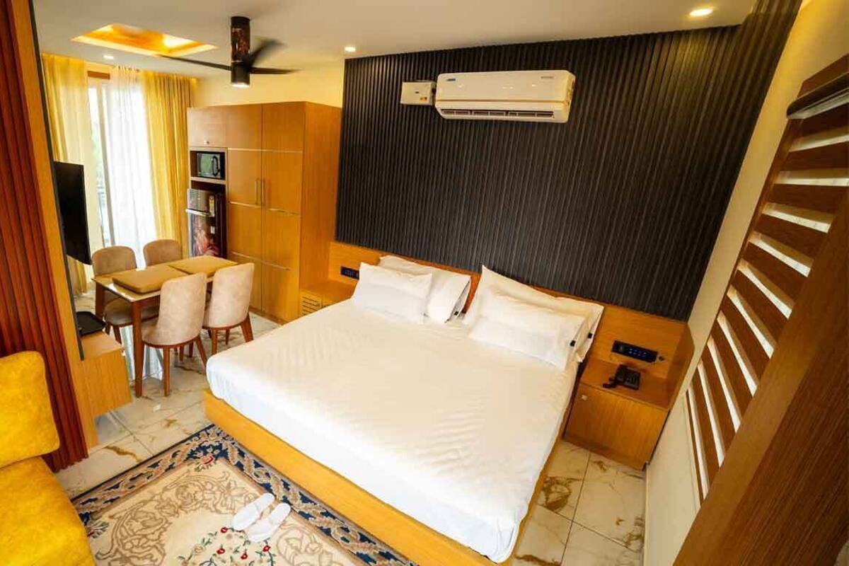 A hotel room with a large bed, a desk with a chair, a flat-screen TV, and a wardrobe.