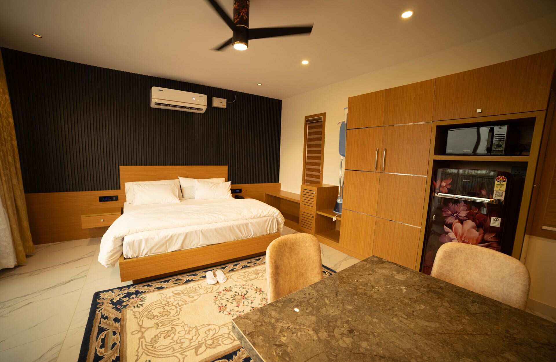 Habitación de hotel con cama, escritorio, silla, armario y refrigerador.