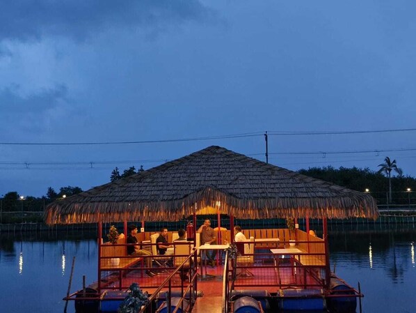A thatched-roof boat with a covered seating area and a small bar.