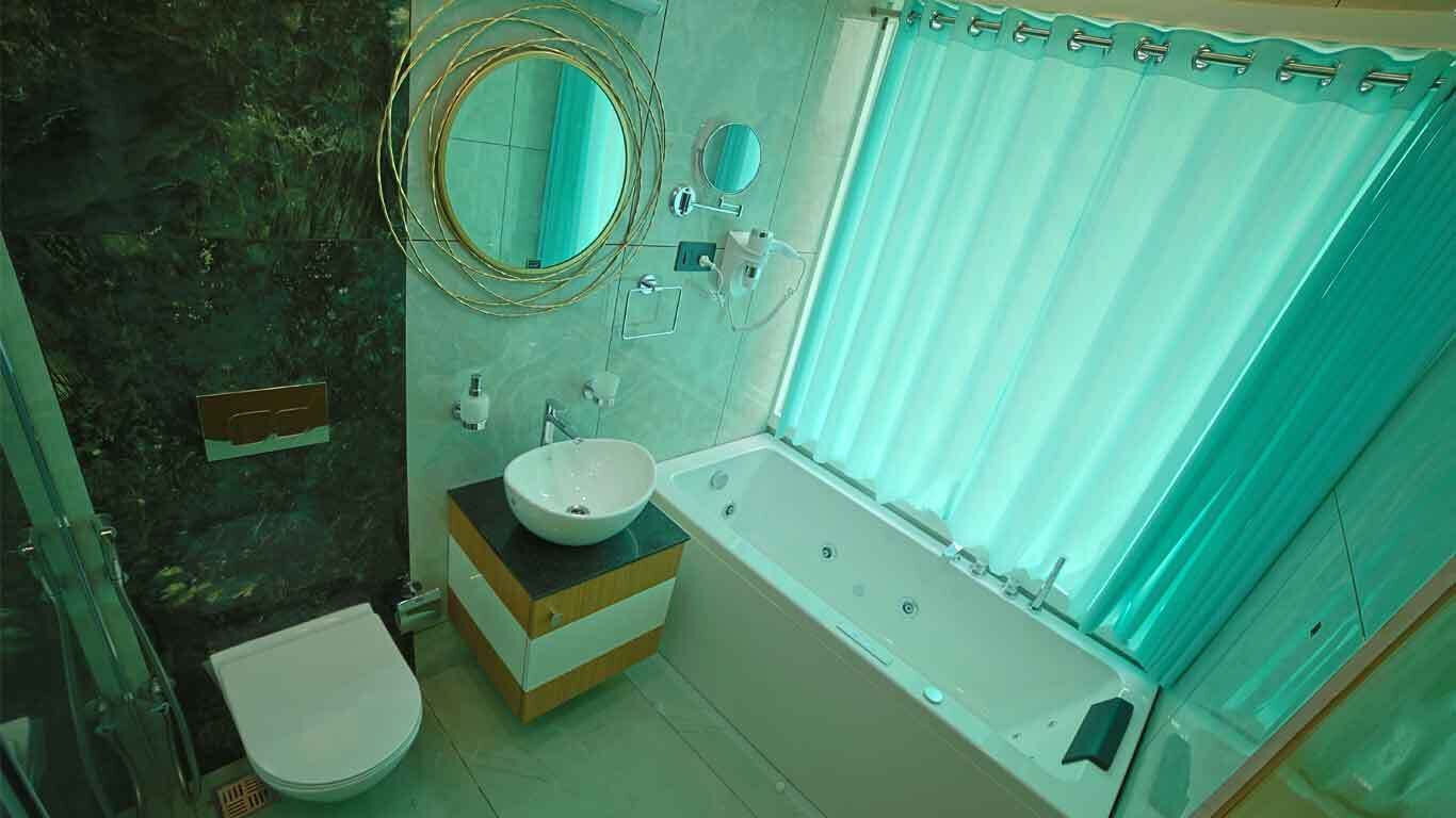 A bathroom with a bathtub, a sink with a bowl, a toilet, a mirror, and a shower curtain.