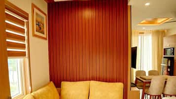Une chambre d’hôtel moderne dotée d’un canapé d’angle, d’un coin repas et d’une télévision.
