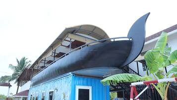 Una gran estructura curva que recuerda a una barca o canoa, con un edificio azul al frente.