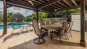 An outdoor patio with a pool, a covered seating area, and a grill. - Relaxing 4BR Villa with Pool, Hot Tub & Comfort at Sabanaliber 205 by Bocobay (Noord)