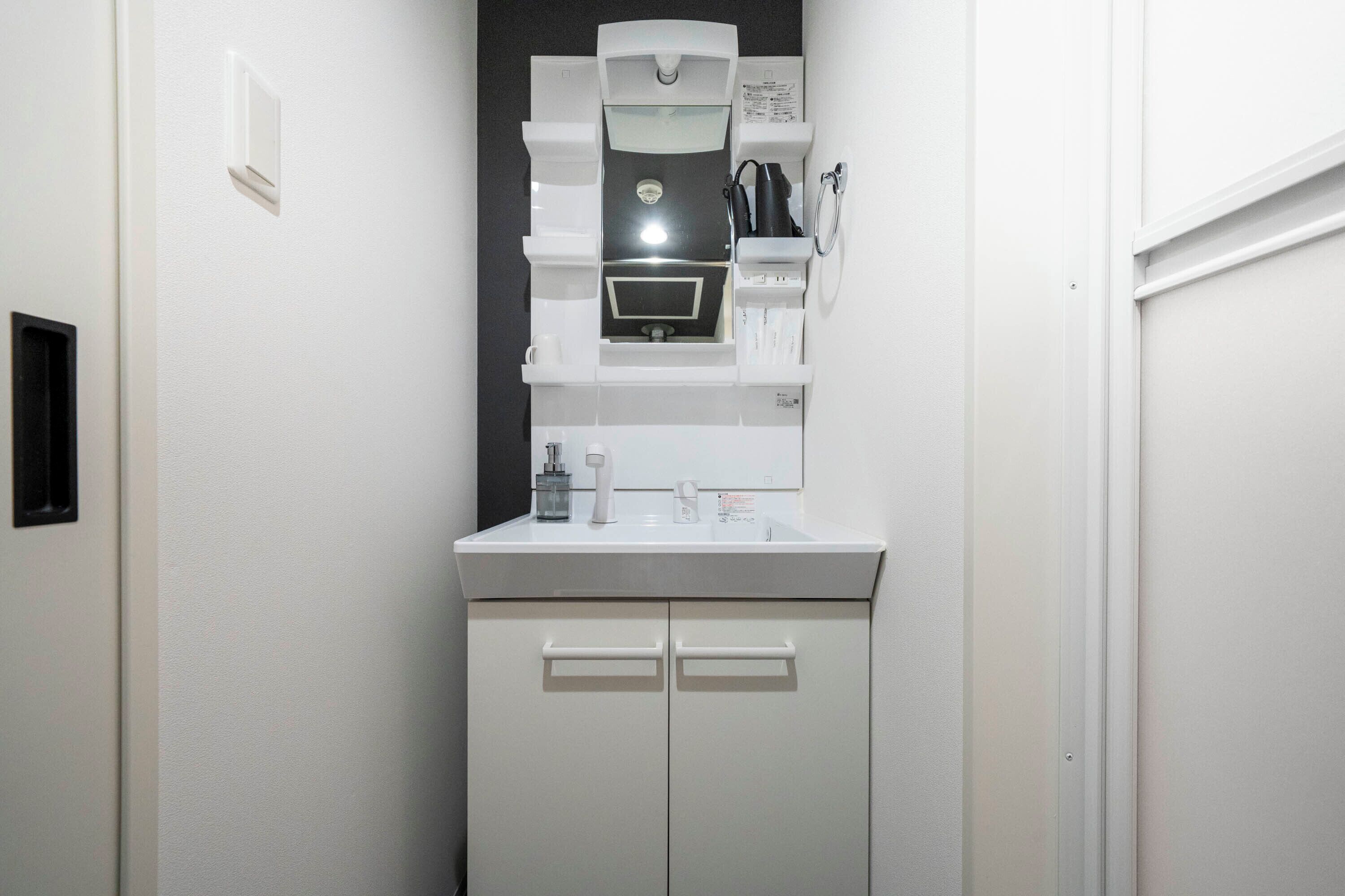 A small, white bathroom with a mirror, sink, and cabinet.