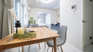 Un espace repas moderne avec une table en bois, des chaises à motifs noir et blanc, une bougie et une plante en pot.