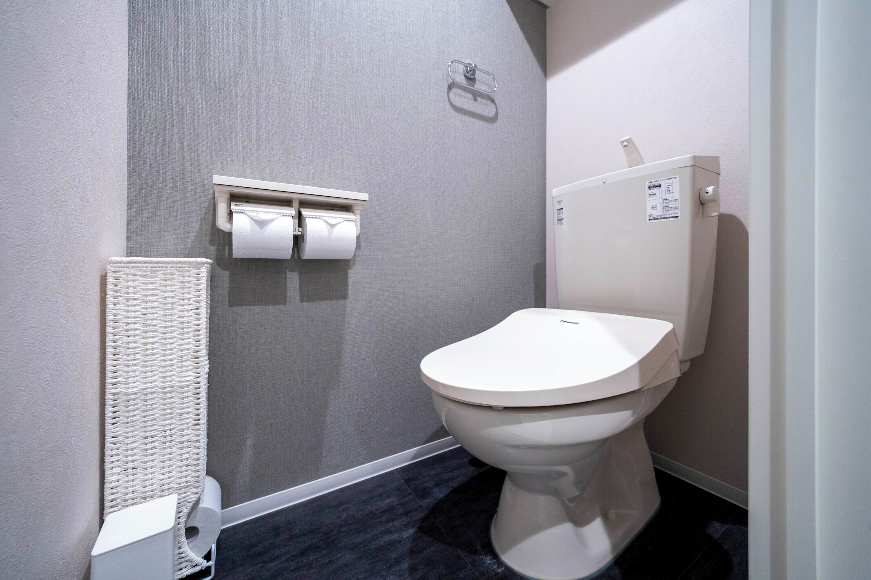 A modern bathroom with a white toilet, a towel rack, and a paper towel dispenser.