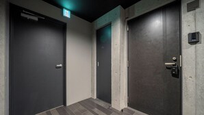 Un couloir avec trois portes, chacune équipée d’un lecteur de carte à puce et d’une indication du numéro de la pièce : 102.