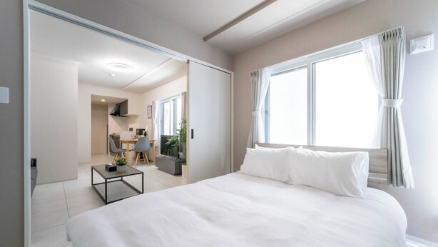 Une chambre d’hôtel moderne, dotée d’un grand lit, d’une petite table, d’un bureau et offrant une vue sur l’extérieur par une fenêtre.