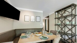 Comedor con una mesa de madera dispuesta para cuatro personas, rodeado de asientos acolchados.