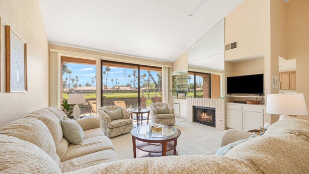 A spacious living room with a fireplace, comfortable seating, and a large TV.