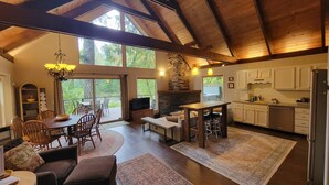 A spacious living area with a dining table, sofas, and a stone fireplace.