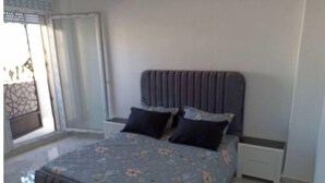 Ein Schlafzimmer mit einem Bett, Kissen, einem Nachttisch und einem Fenster mit Aussicht.
