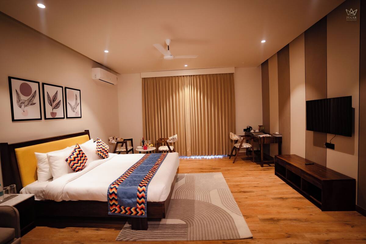 Una habitación de hotel moderna con una cama grande, un escritorio, una silla, un televisor y un ventilador de techo.