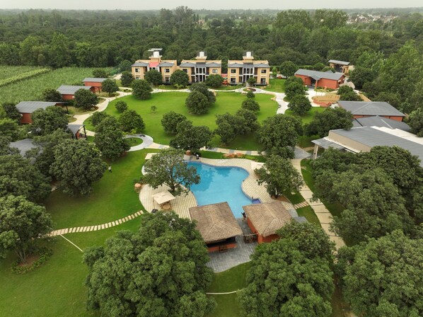 A large building with multiple rooms, a swimming pool, and surrounding greenery.