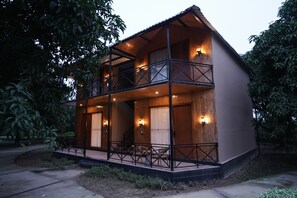 A two-story wooden house with a balcony, a staircase, and a small porch area.
