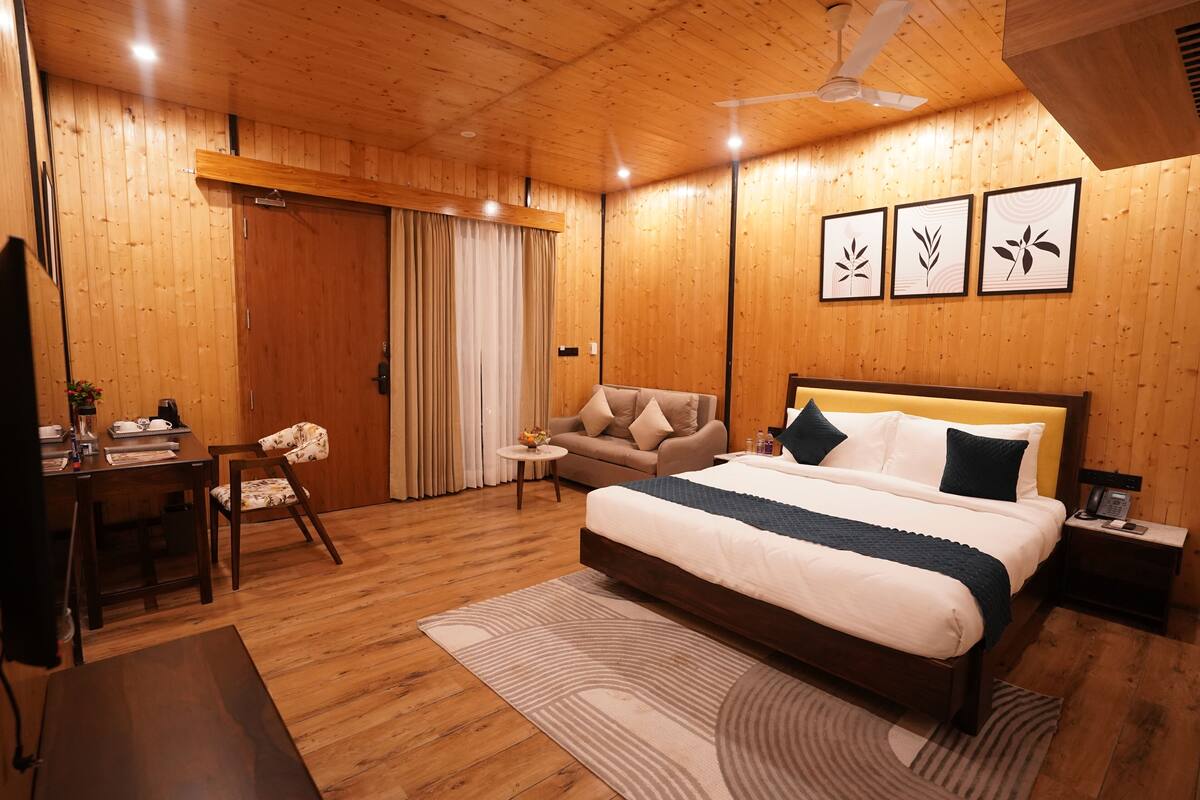 Un dormitorio con paneles de madera, una cama, un sofá, un escritorio y un ventilador de techo.