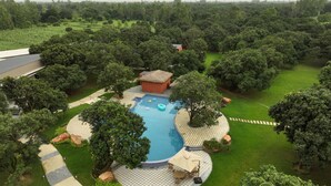 Vista aérea de una propiedad residencial con piscina, patio amoblado y césped bien cuidado.