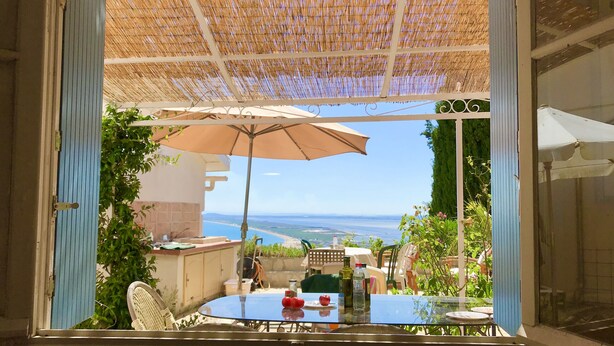 A balcony with a table, chairs, and a large umbrella. - Sète - La Vigie Singulière (Sète)
