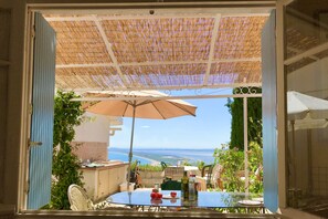 Ein Balkon mit Tisch, Stühlen und einem großen Sonnenschirm.