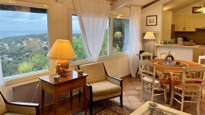 A cozy living room with a sofa, chairs, a small table, and a view of the countryside. - Sète - La Vigie Singulière (Sète)