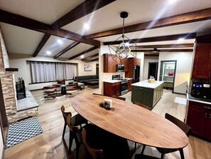 Una cocina moderna con armarios de madera oscura, una isla central y un comedor con mesa y sillas de madera.