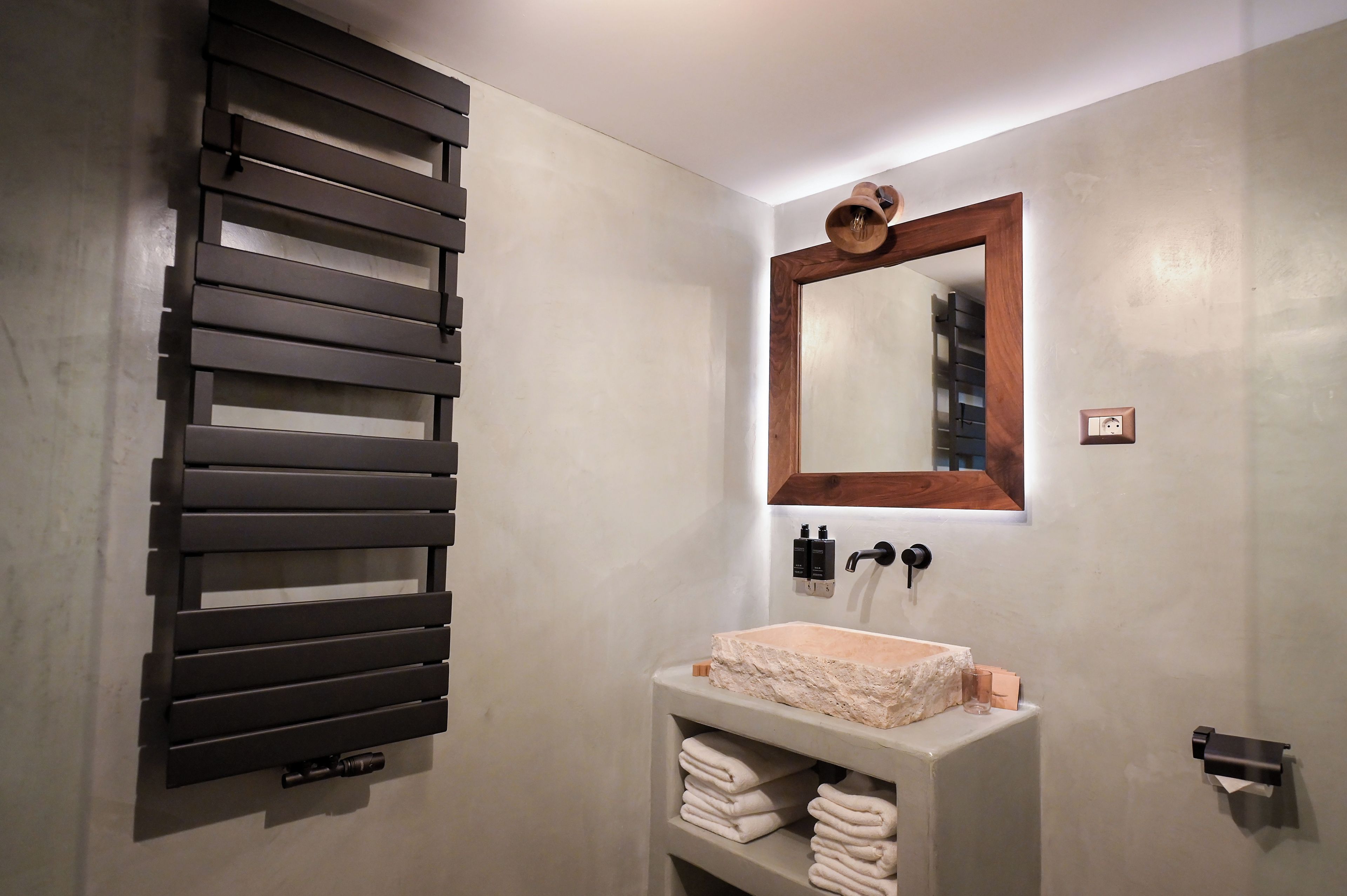 A bathroom with a modern sink, a towel rack, and a mirror with a wooden frame.
