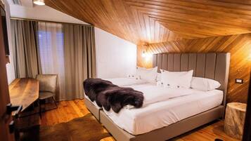 Een slaapkamer met een houten plafond, een bed met wit beddengoed, een stoel en een hond.
