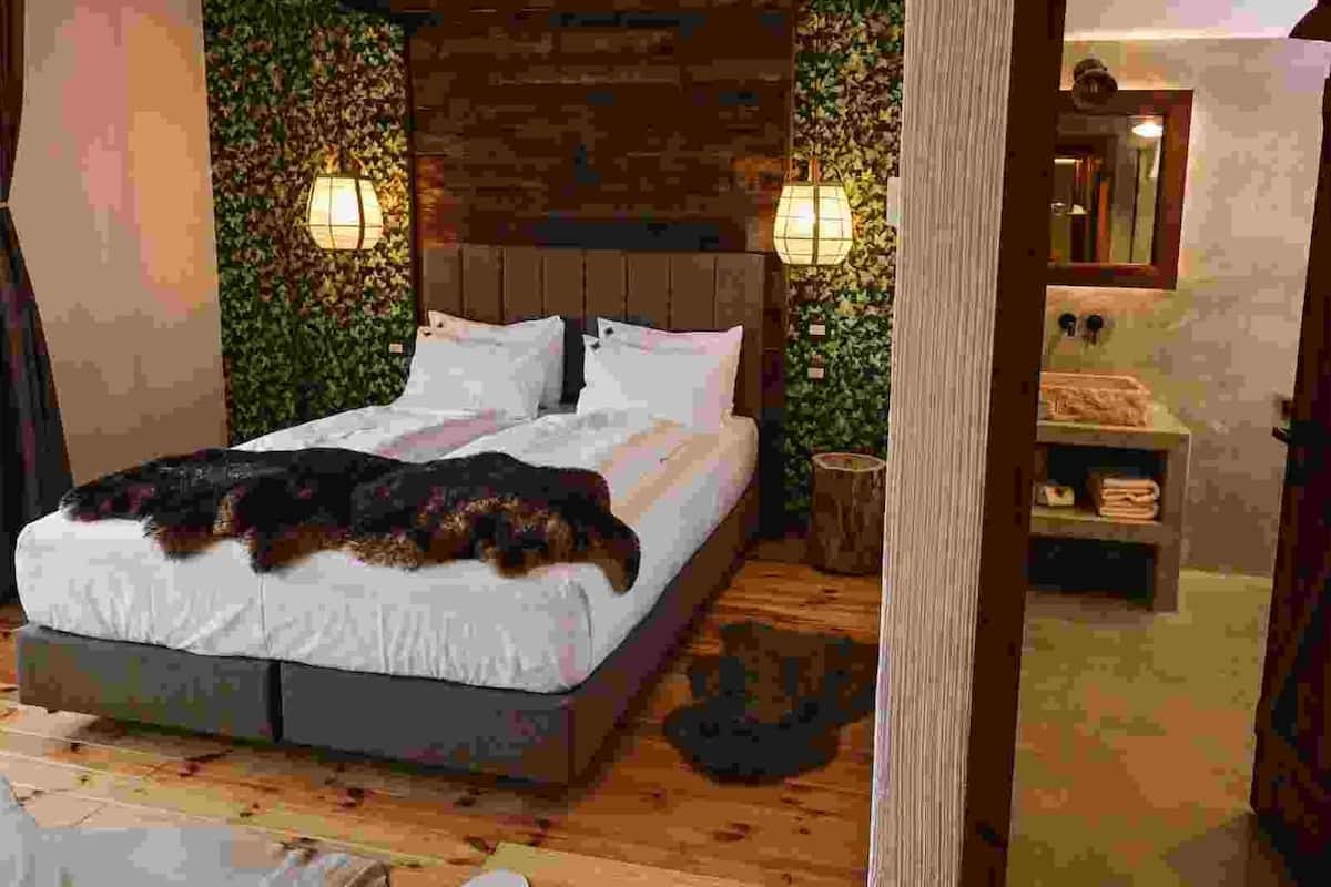 Une chambre à coucher avec un lit, une tête de lit en bois et une table de chevet avec une lampe.