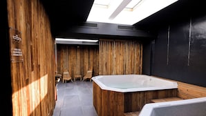 Une salle de spa moderne avec des murs en bois, une grande baignoire sur pieds et une lucarne.