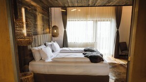 Une chambre avec un grand lit, un luminaire suspendu et une vue sur l’extérieur par une fenêtre.