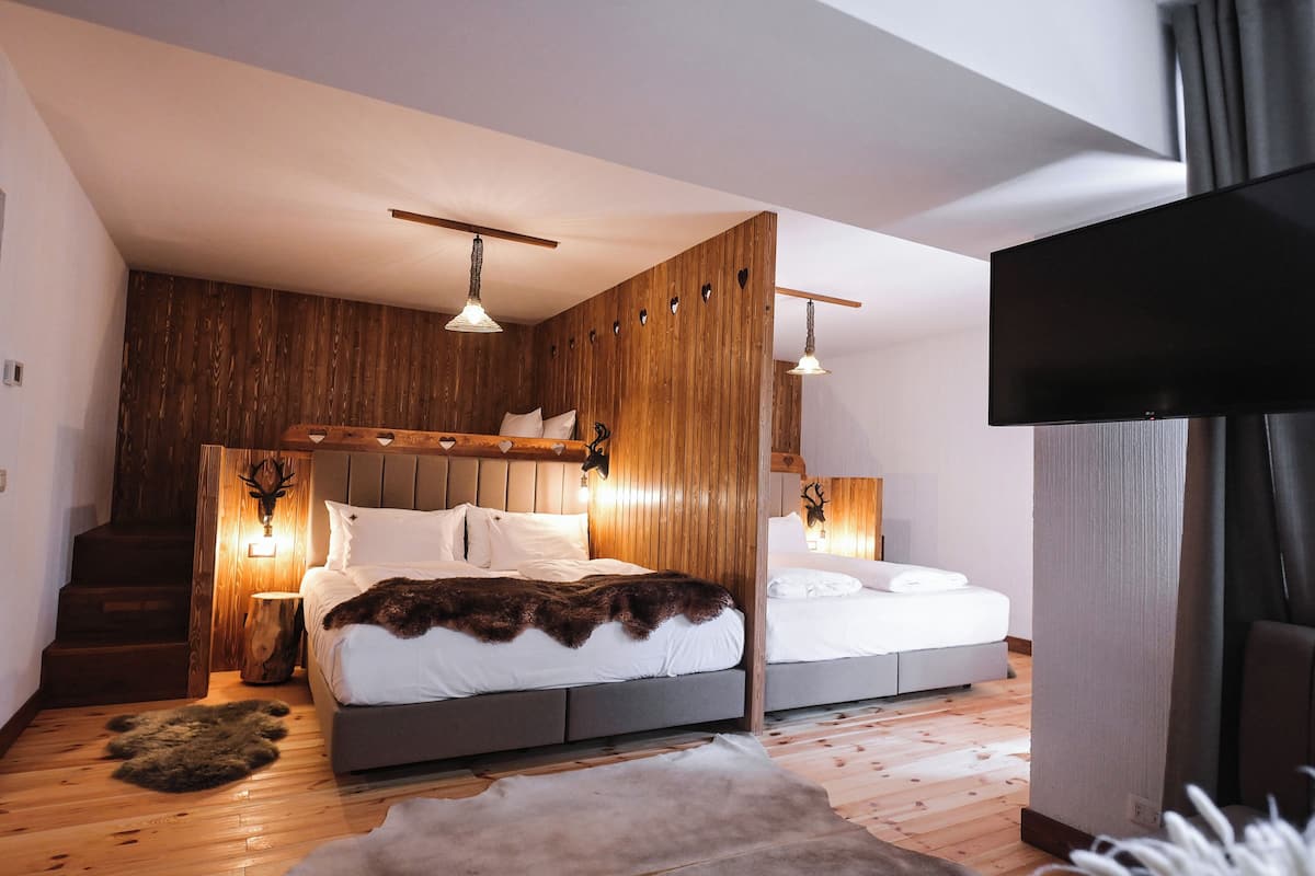 Une chambre moderne avec un mur d’accent en bois, deux lits, un grand téléviseur à écran plat et un escalier.