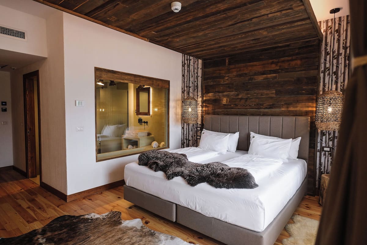 Une chambre avec un grand lit, un plafond en bois et un miroir au mur.