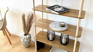 Una consola de madera de tres niveles con un espejo encima, un libro, velas y jarrones decorativos.