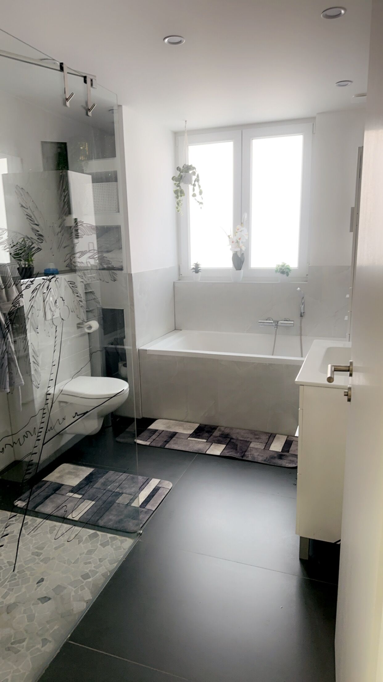 A modern bathroom with a glass shower enclosure, a freestanding bathtub, and a toilet.