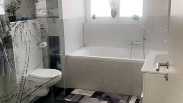 A modern bathroom with a glass shower enclosure, a freestanding bathtub, and a toilet.