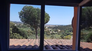 A room with a large window overlooking a terraced vineyard and a distant town. - Vila with private pool, sea view 7km away Pets welcome (Calonge)