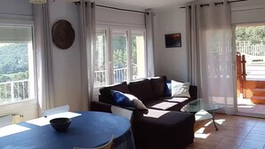 A living room with a dining table, a sofa, and a glass coffee table. - Vila with private pool, sea view 7km away Pets welcome (Calonge)