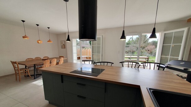 A modern kitchen with a central island, pendant lighting, and a view to the outdoors. - Sunny vacation home. Ideally located between lake, beach and forest. (Sanguinet)