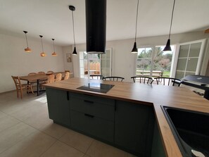 A modern kitchen with a central island, pendant lighting, and a view to the outdoors.