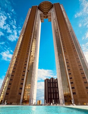 A tall hotel with a central atrium and a pool area at the base.