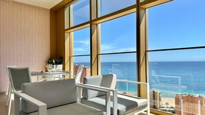 Quarto moderno com grandes janelas, varanda e vista para o mar.