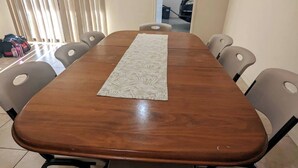 A wooden dining table with a patterned runner, surrounded by grey chairs with cut-out backrests.