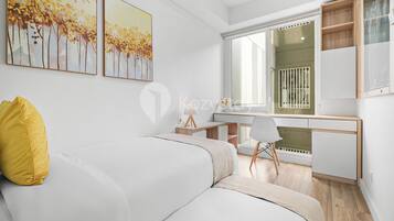 A modern living room with a white sofa, a yellow pillow, a desk with a chair, and two paintings on the wall.