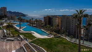 A resort with a large pool, palm trees, and a view of the ocean. - Sunset Cliffs Residence (Benidorm)
