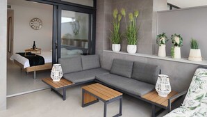 A modern living room with a grey sofa, wooden coffee tables, and white planters with green plants. - Sunset Cliffs Residence (Benidorm)