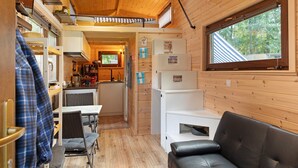 Una cabaña compacta con kitchenette, comedor y una zona de estar acogedora.