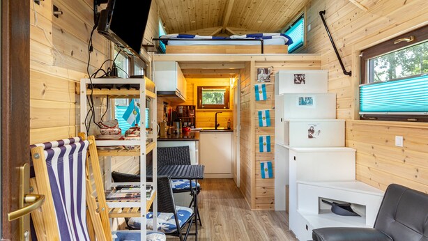 Une petite cabine comprenant un coin cuisine, un canapé, un espace repas et une mezzanine servant de chambre.
