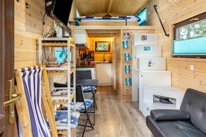 A compact cabin with a kitchenette, a sofa, a dining area, and a sleeping loft.