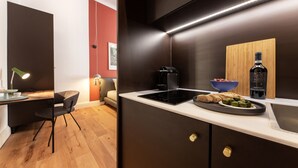 Een moderne keuken met een zwart inductiefornuis, een houten plank, een fles wijn en een schaal olijven.