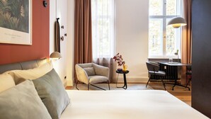 Een hotelkamer met een bed, een stoel, een bureau en een raam met gordijnen.